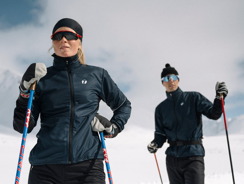 Two people looking over the camera, both wearing Trimtex Ambition skiing jacket and pants