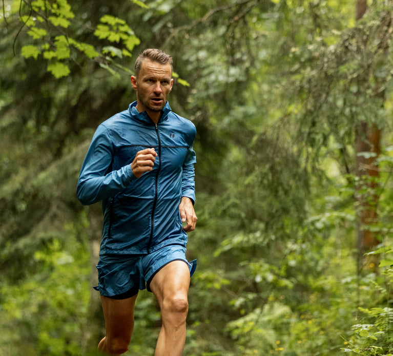 Triathlete running in the forest wearing the Fast Running jacket and shorts