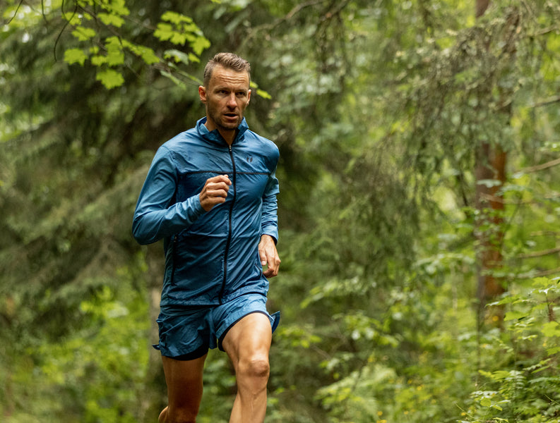 Triathlete running in the forest wearing the Fast Running jacket and shorts