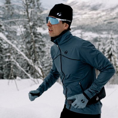 Man running in the snowy mountains, wearing Trimtex Instinct jacket and Pulse Merino headband.